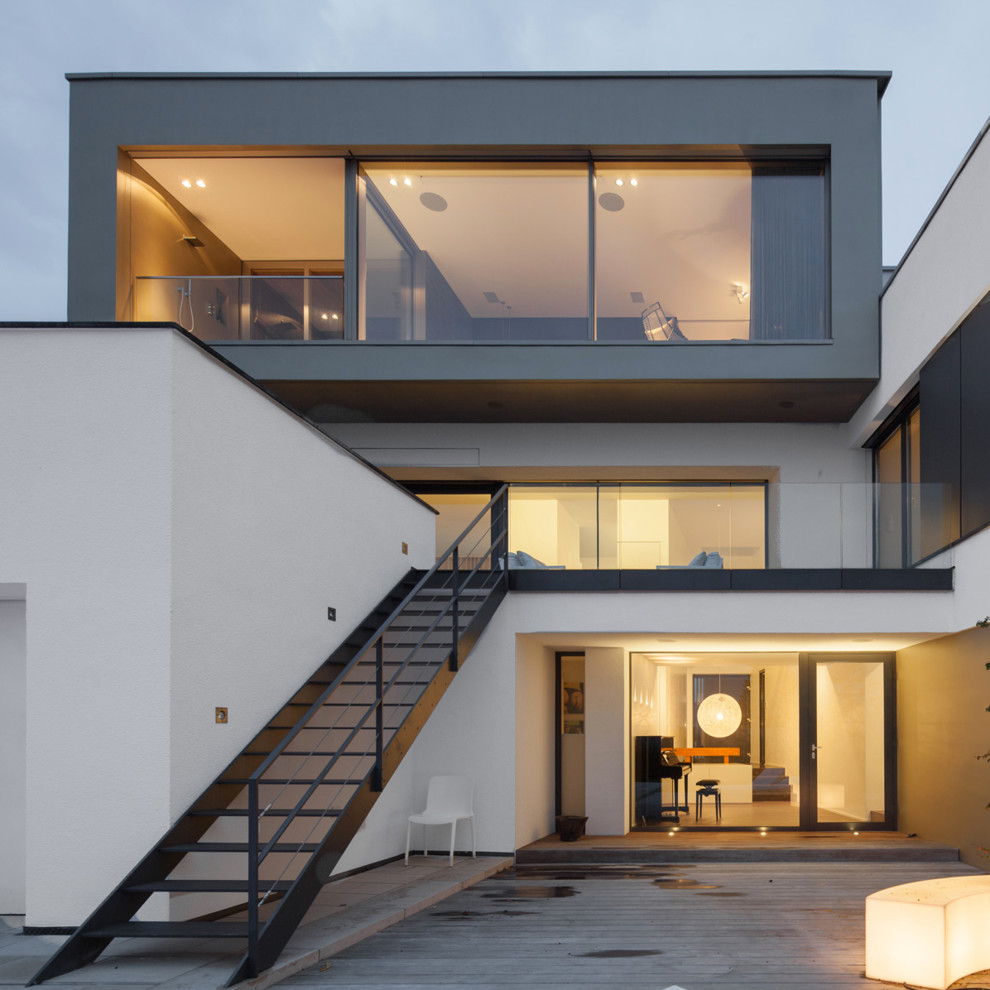 Inspiration for a white modern house exterior in Frankfurt with three floors, mixed cladding and a flat roof.