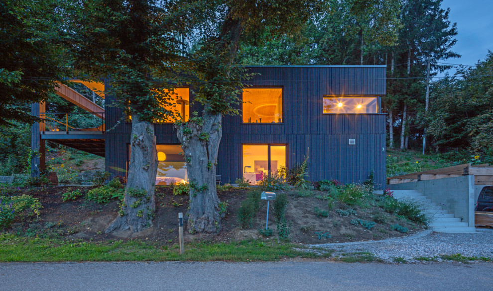 Cette image montre une façade de maison grise design en bois de taille moyenne et à un étage avec un toit plat.