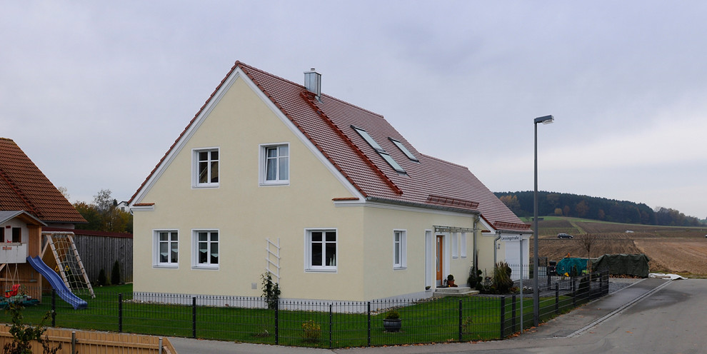 Mittelgroßes, Zweistöckiges Klassisches Haus mit Putzfassade, gelber Fassadenfarbe und Satteldach in München