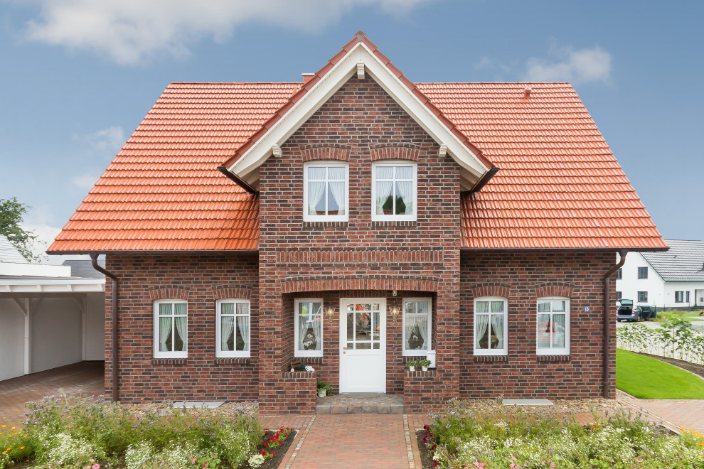 Ejemplo de fachada de casa roja rural de tamaño medio de una planta con revestimiento de ladrillo, tejado a cuatro aguas y tejado de teja de barro