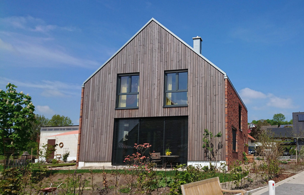Mittelgroßes Modernes Haus mit grauer Fassadenfarbe, Satteldach, Ziegeldach, grauem Dach und Verschalung in Sonstige