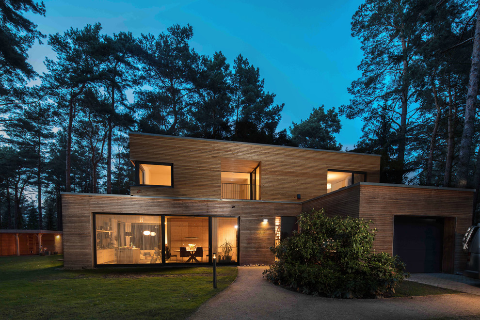 Cette image montre une grande façade de maison beige design en bois avec un toit plat.