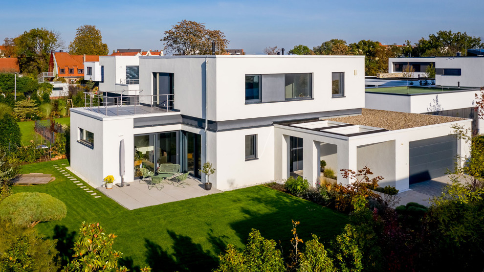 Свежая идея для дизайна: двухэтажный, белый частный загородный дом среднего размера в современном стиле с облицовкой из цементной штукатурки и плоской крышей - отличное фото интерьера