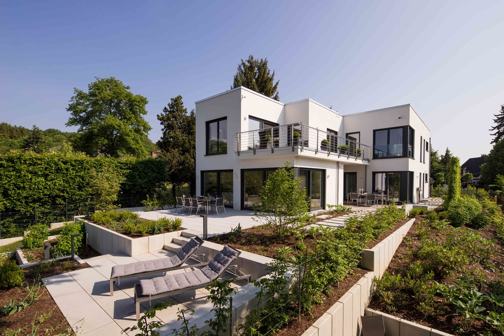На фото: двухэтажный, белый, огромный частный загородный дом в стиле модернизм с облицовкой из цементной штукатурки и плоской крышей