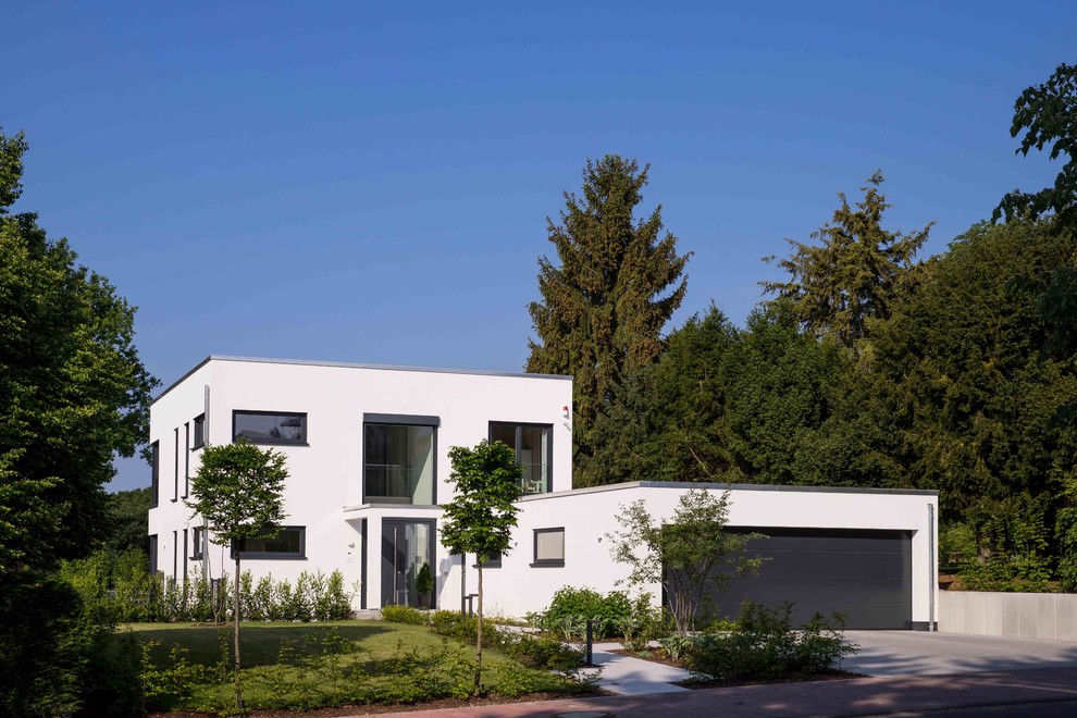 Zweistöckiges, Mittelgroßes Modernes Einfamilienhaus mit Putzfassade, weißer Fassadenfarbe und Flachdach in Sonstige