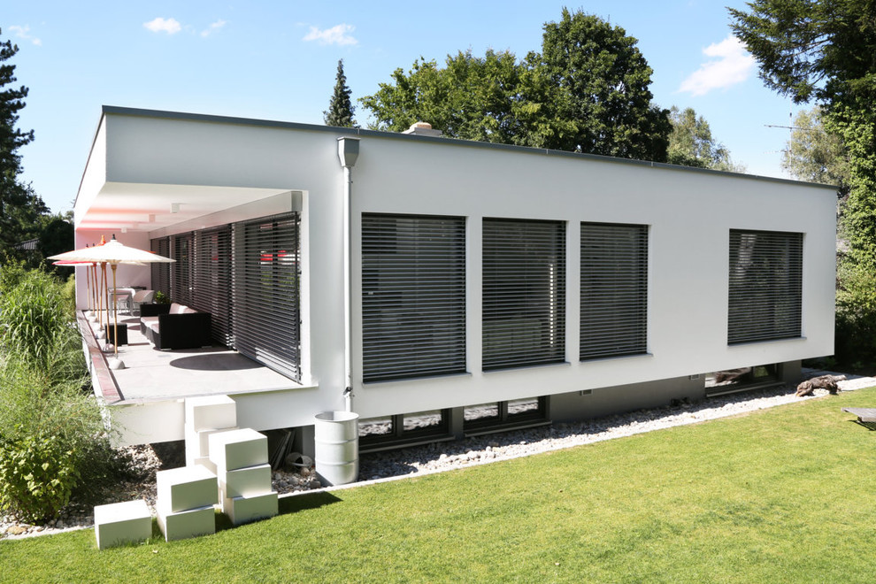 Идея дизайна: белый, большой, двухэтажный частный загородный дом в современном стиле с плоской крышей и облицовкой из цементной штукатурки