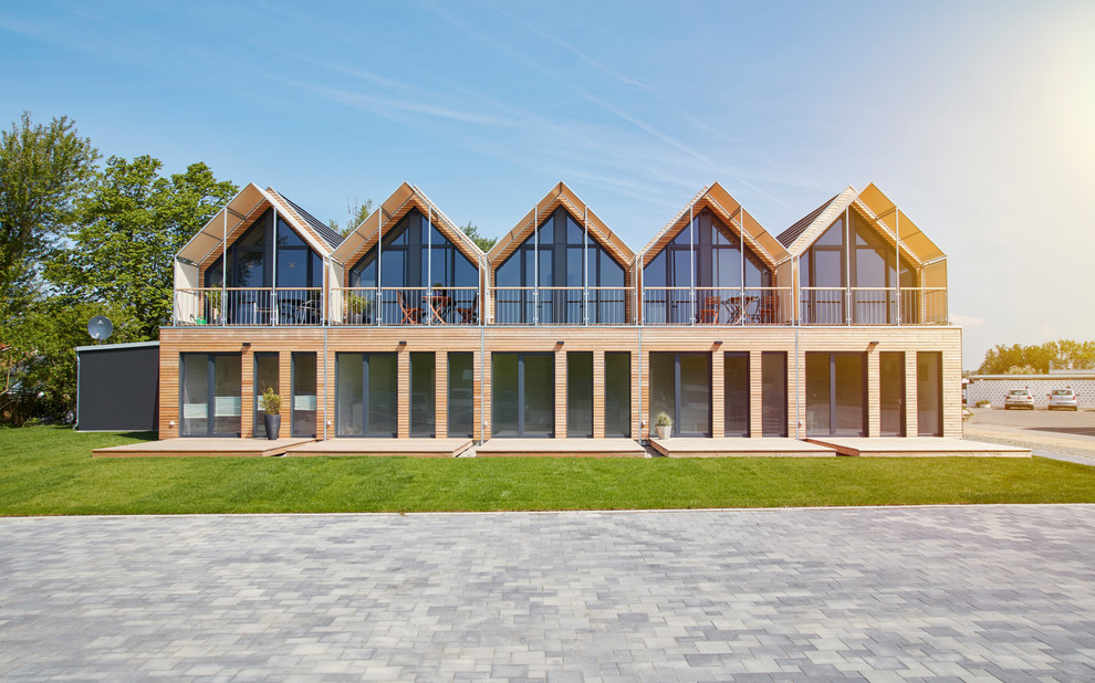 Foto della facciata di una casa a schiera grande marrone scandinava a due piani con rivestimento in legno, tetto a capanna e copertura in metallo o lamiera