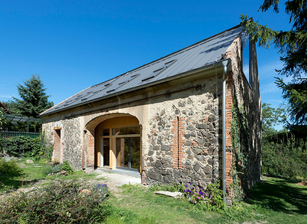 Imagen de fachada de casa contemporánea con revestimiento de madera, tejado a dos aguas y tejado de metal