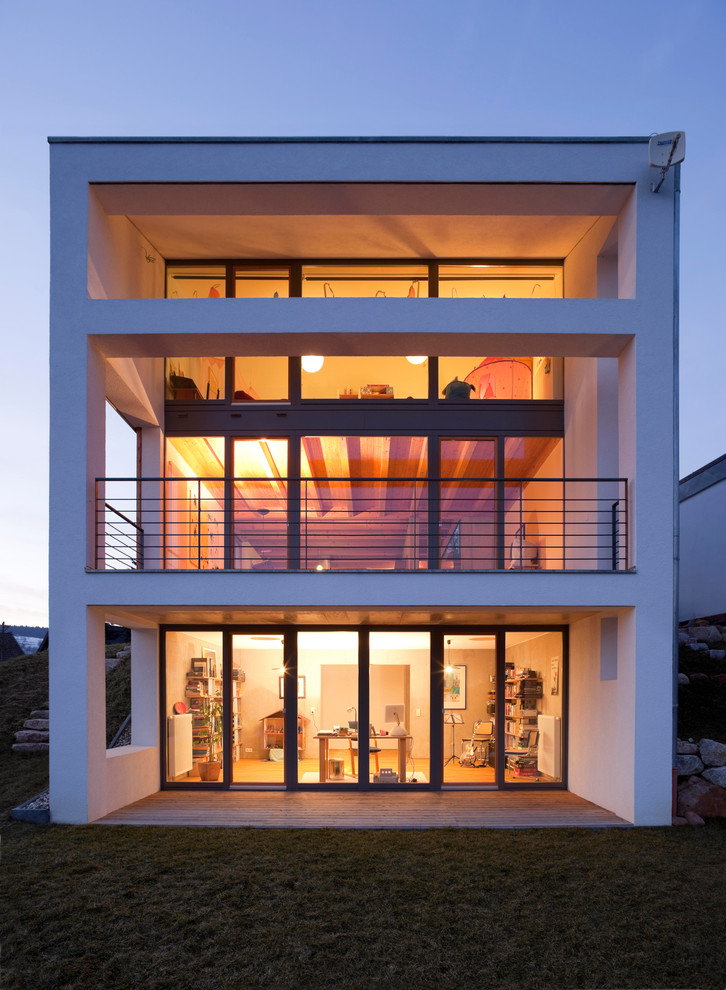 Foto della facciata di una casa grande bianca moderna a tre piani con rivestimento in vetro e tetto piano