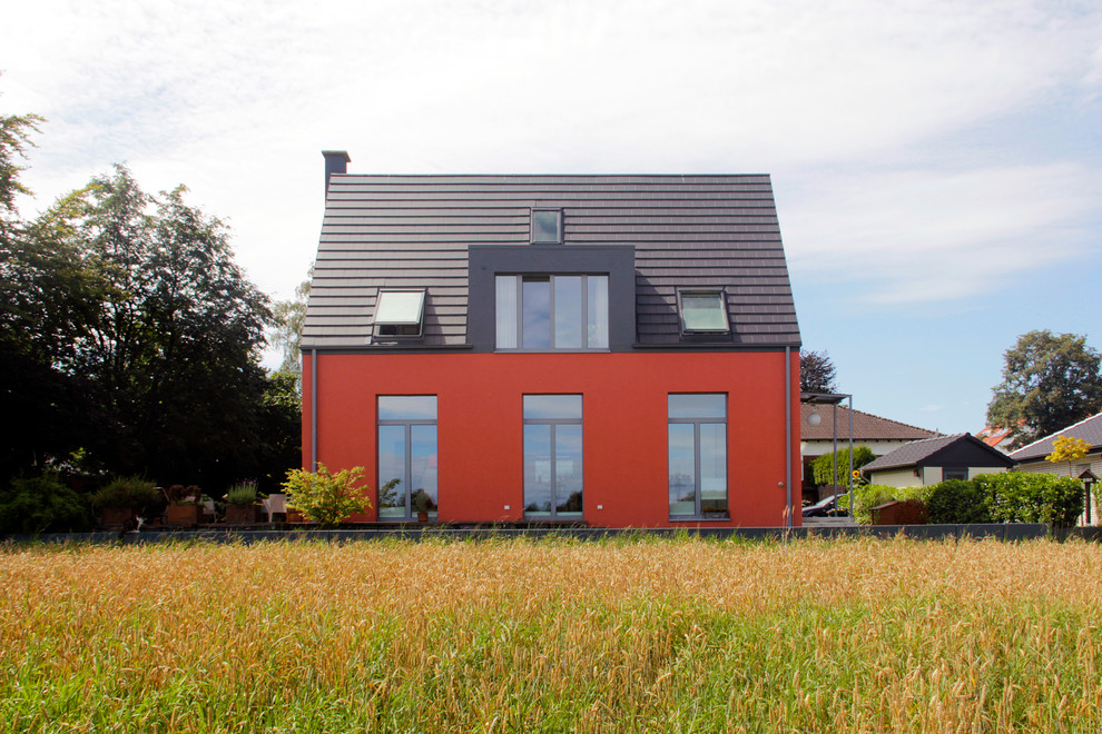 Пример оригинального дизайна: двухэтажный, красный дом среднего размера в современном стиле с двускатной крышей