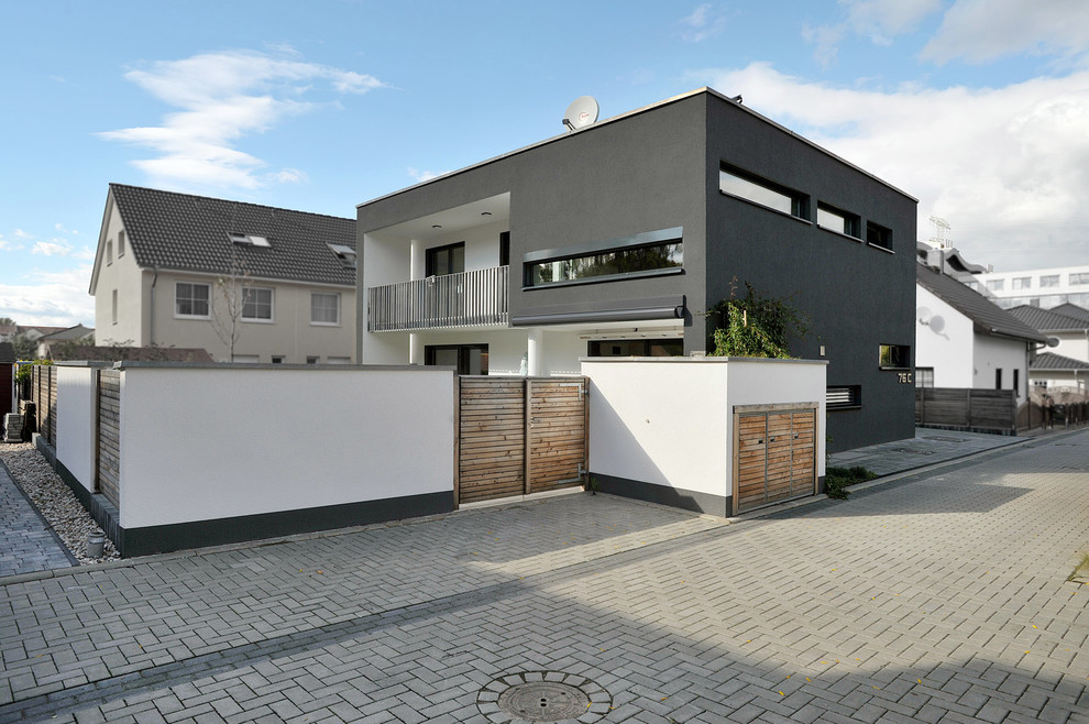 Idées déco pour une grande façade de maison noire moderne en stuc à un étage avec un toit plat.