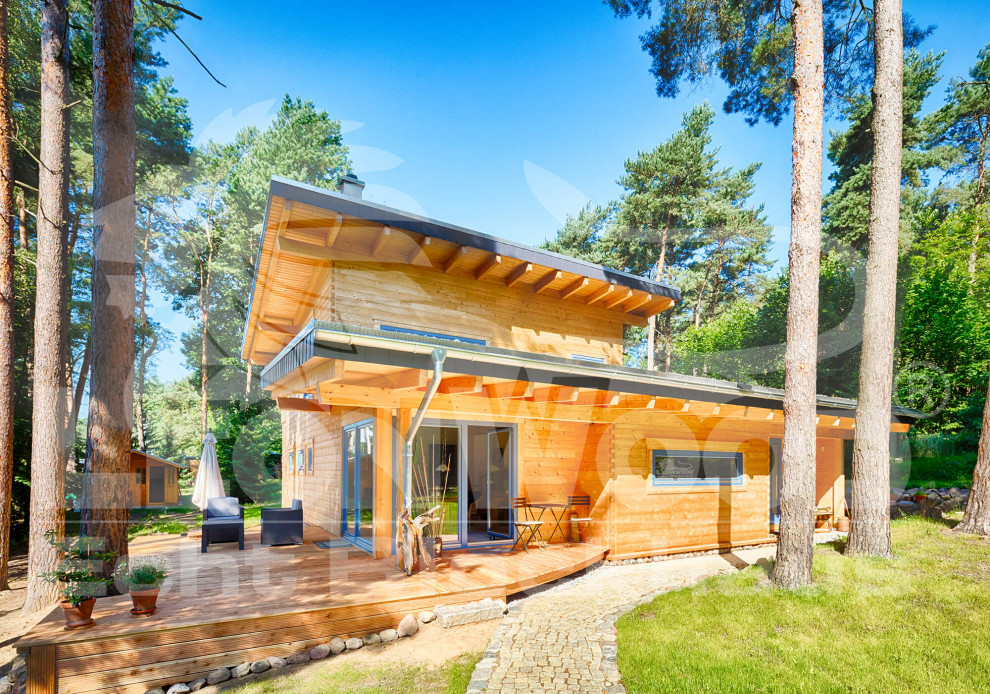 На фото: двухэтажный, деревянный, коричневый частный загородный дом среднего размера в скандинавском стиле с односкатной крышей и зеленой крышей с