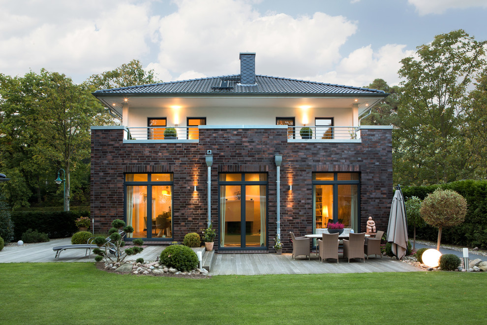 Réalisation d'une façade de maison multicolore design en brique de taille moyenne et à un étage avec un toit à quatre pans et un toit en tuile.