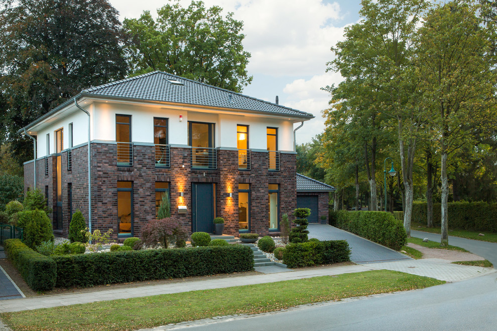 Modelo de fachada de casa multicolor actual de tamaño medio de dos plantas con revestimiento de ladrillo, tejado a cuatro aguas y tejado de teja de barro