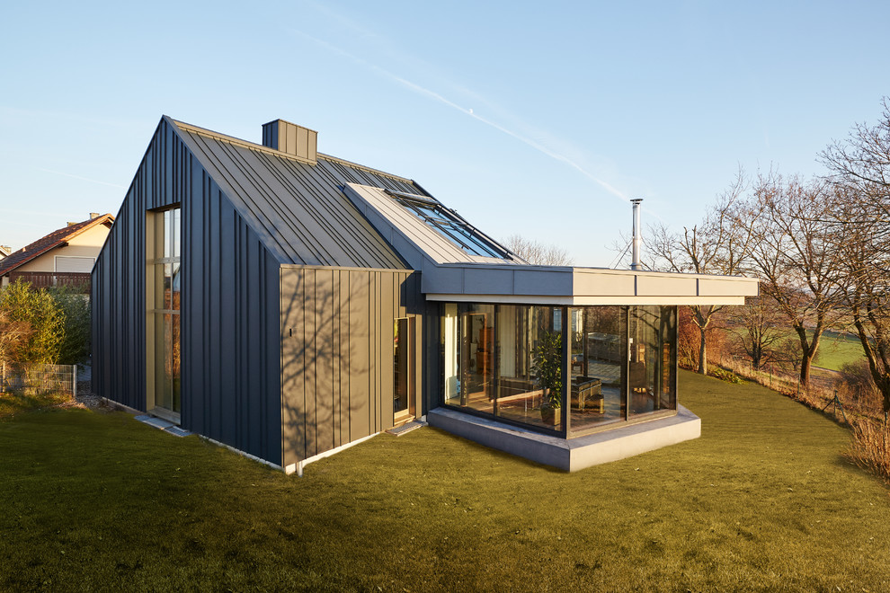 Aménagement d'une façade de maison grise contemporaine de plain-pied avec un toit à deux pans.