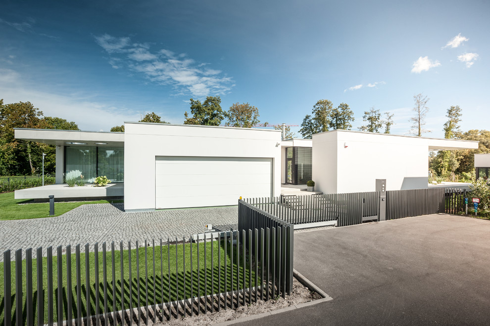 Foto de fachada de casa blanca moderna de una planta con revestimiento de estuco y tejado plano
