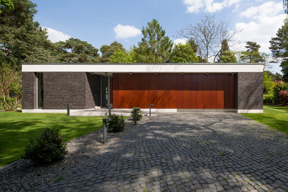 Aménagement d'une façade de maison grise moderne en pierre de plain-pied et de taille moyenne avec un toit plat.