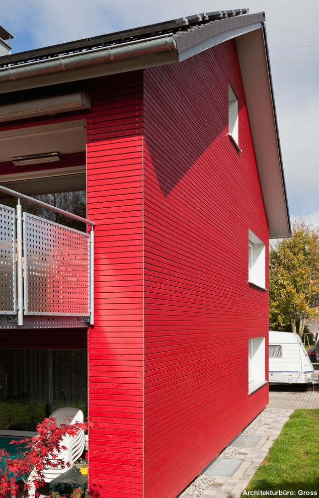 Cette image montre une façade de maison rouge design en bois.