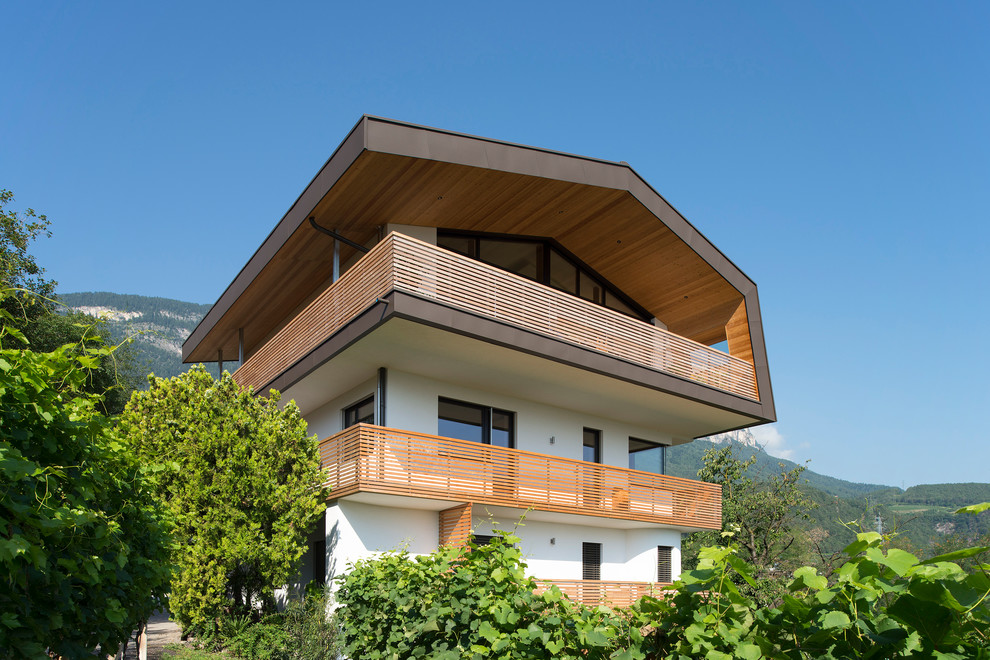 Immagine della villa multicolore moderna a tre piani con tetto a capanna e rivestimento in stucco