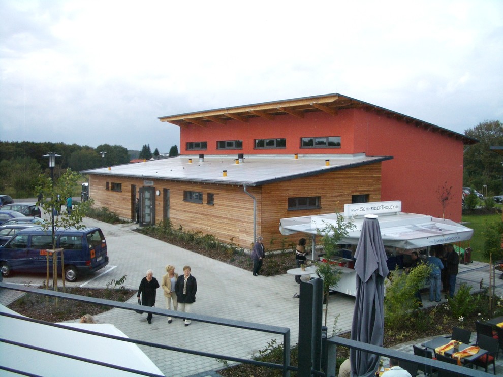 Aménagement d'une façade de maison rouge moderne en bois de plain-pied avec un toit en appentis.