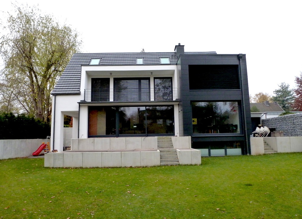 Идея дизайна: частный загородный дом в современном стиле с облицовкой из цементной штукатурки и черепичной крышей