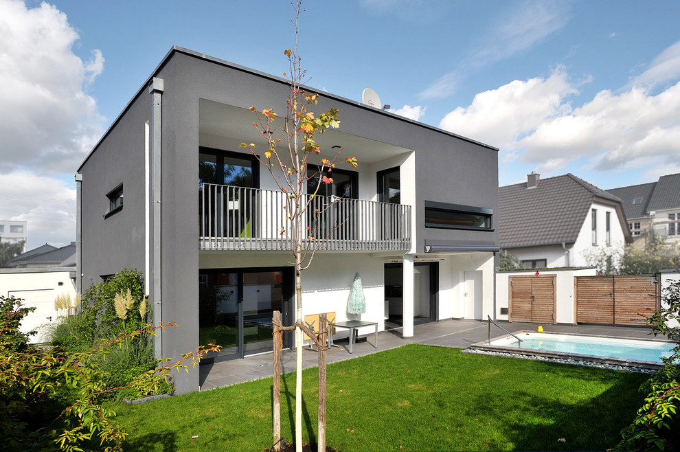 This is an example of a large and black modern two floor render detached house in Berlin with a flat roof.