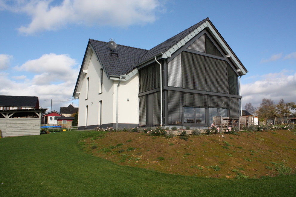Foto de fachada de casa blanca contemporánea grande de dos plantas con revestimiento de estuco, tejado a dos aguas y tejado de teja de barro
