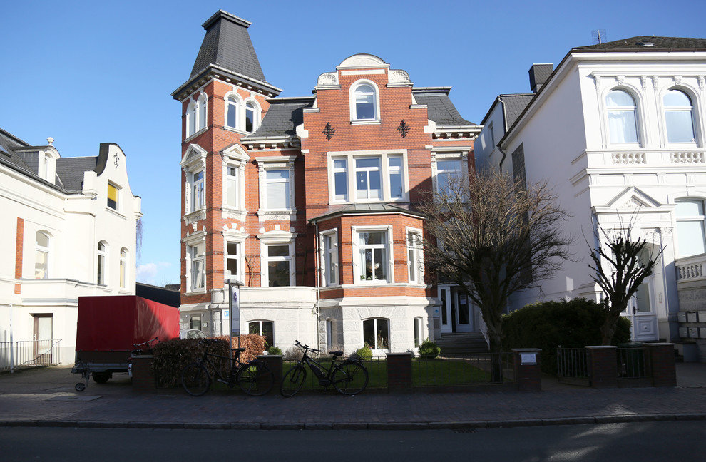 Einstöckiges Shabby-Style Haus mit Backsteinfassade, roter Fassadenfarbe und Mansardendach in Bremen