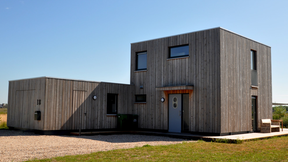 Cette image montre une façade de maison marron design en bois de taille moyenne et à un étage avec un toit plat.