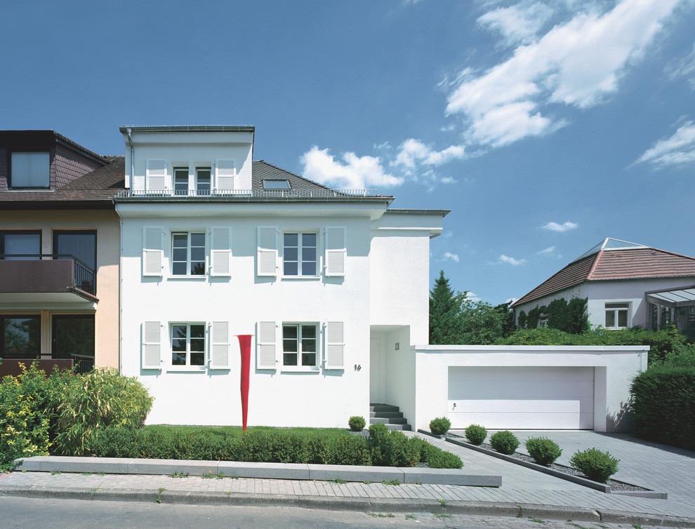 На фото: трехэтажный, белый дом среднего размера в классическом стиле с облицовкой из цементной штукатурки с