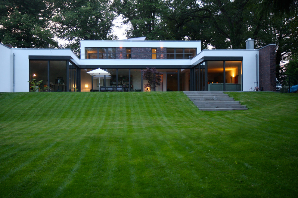 Photo of a white and medium sized contemporary bungalow detached house in Hamburg with a flat roof, mixed cladding and a green roof.