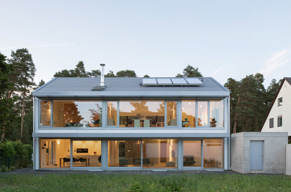 Idée de décoration pour une façade de maison blanche design en verre de taille moyenne et à un étage avec un toit à deux pans.