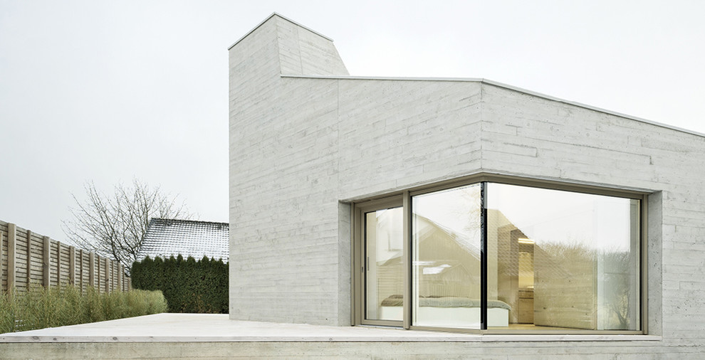 Exemple d'une façade de maison grise moderne en béton de taille moyenne et à un étage avec un toit en appentis.