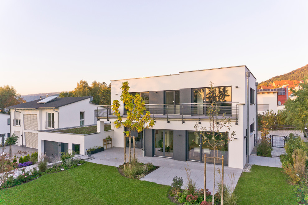Idées déco pour une façade de maison blanche contemporaine en stuc de taille moyenne et à un étage avec un toit plat et un toit végétal.