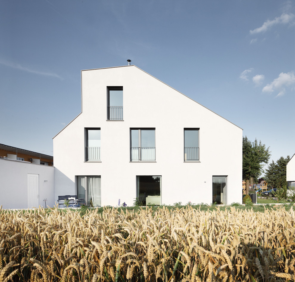 Стильный дизайн: трехэтажный, белый дом среднего размера в современном стиле с односкатной крышей - последний тренд
