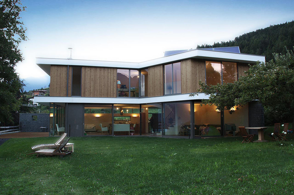 Photo of a medium sized and brown contemporary two floor house exterior in Munich with wood cladding and a flat roof.