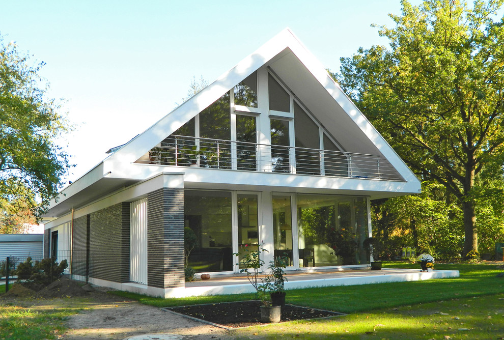 Imagen de fachada gris actual de tamaño medio de dos plantas con revestimientos combinados y tejado a dos aguas