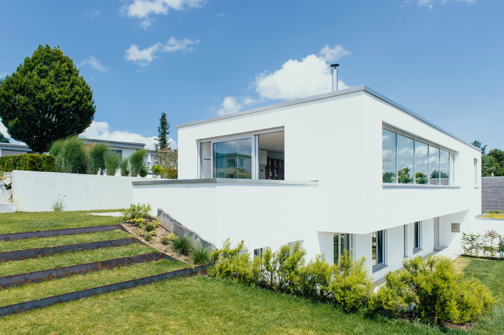 Cette image montre une grande façade de maison blanche design à un étage avec un toit plat.