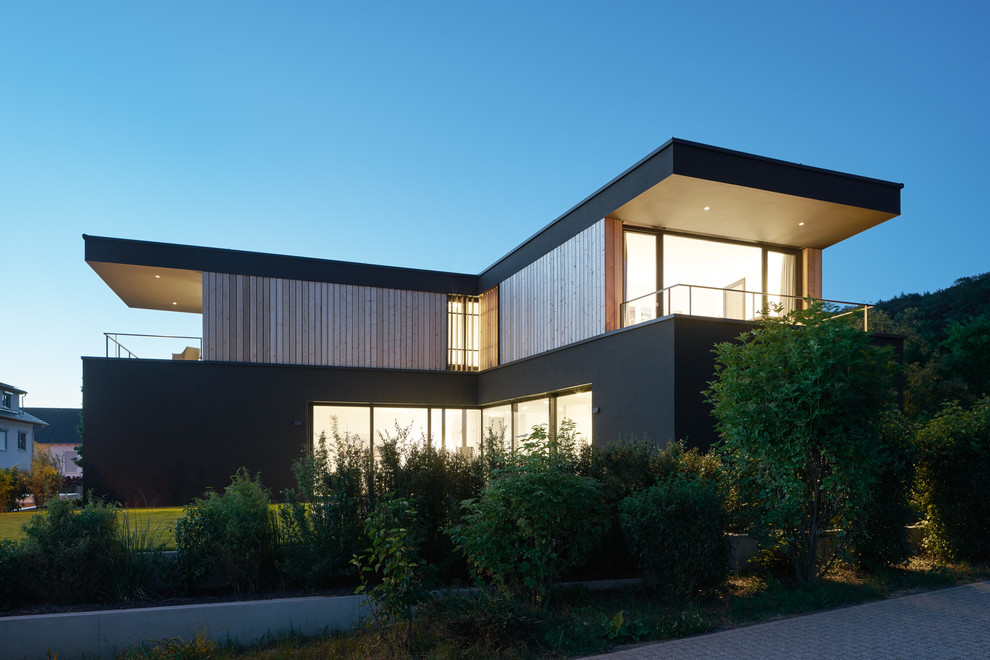 Imagen de fachada negra moderna de tamaño medio de dos plantas con revestimiento de madera y tejado plano