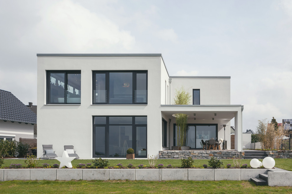 Design ideas for a medium sized and white contemporary two floor render detached house in Dortmund with a flat roof.