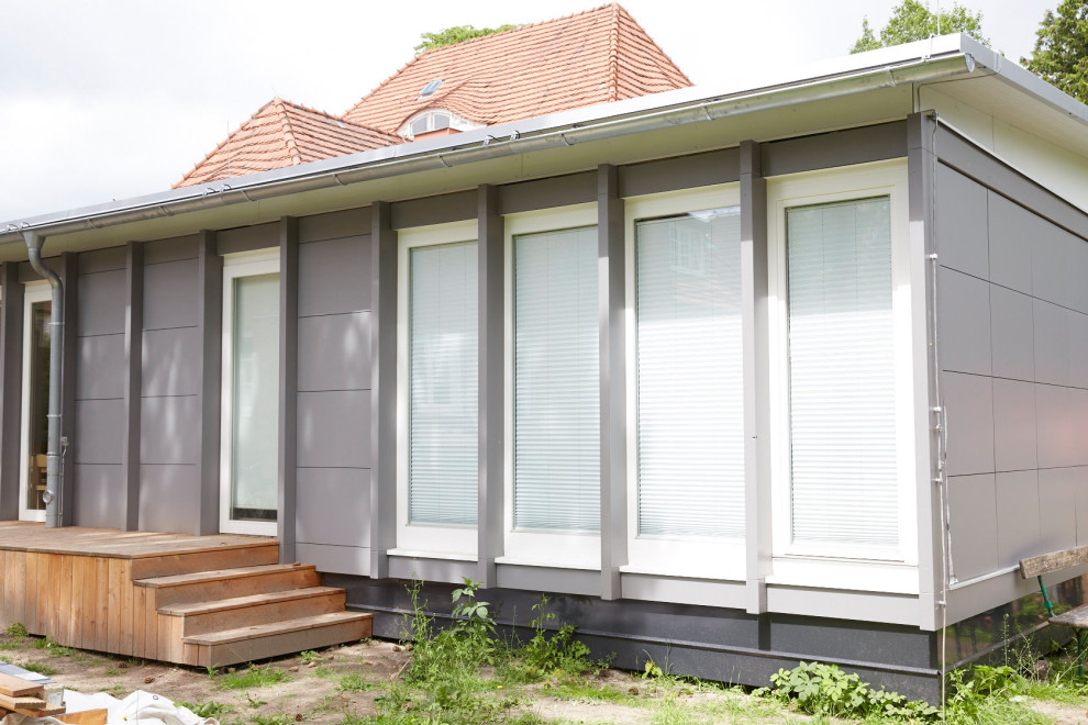 Immagine della facciata di una casa ampia grigia contemporanea a un piano con rivestimento in vinile e tetto piano