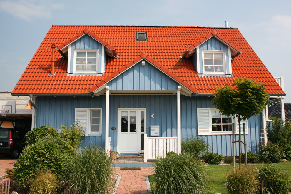 Einstöckiges Landhausstil Einfamilienhaus mit blauer Fassadenfarbe, Satteldach und Ziegeldach in Sonstige