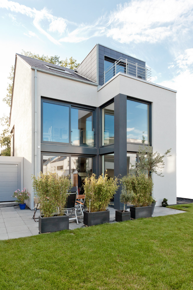 Diseño de fachada blanca contemporánea de tres plantas con tejado a dos aguas