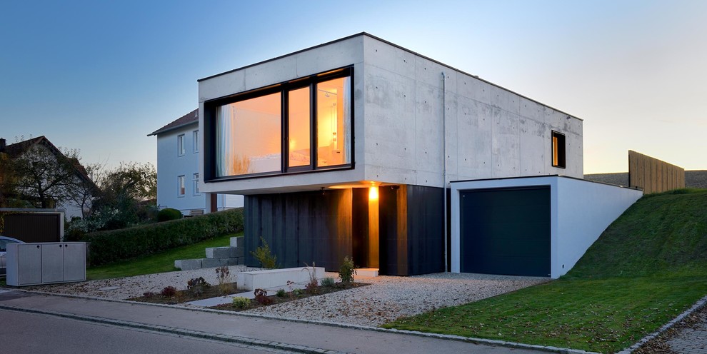 Foto della facciata di una casa piccola grigia contemporanea a due piani con rivestimento in cemento e tetto piano