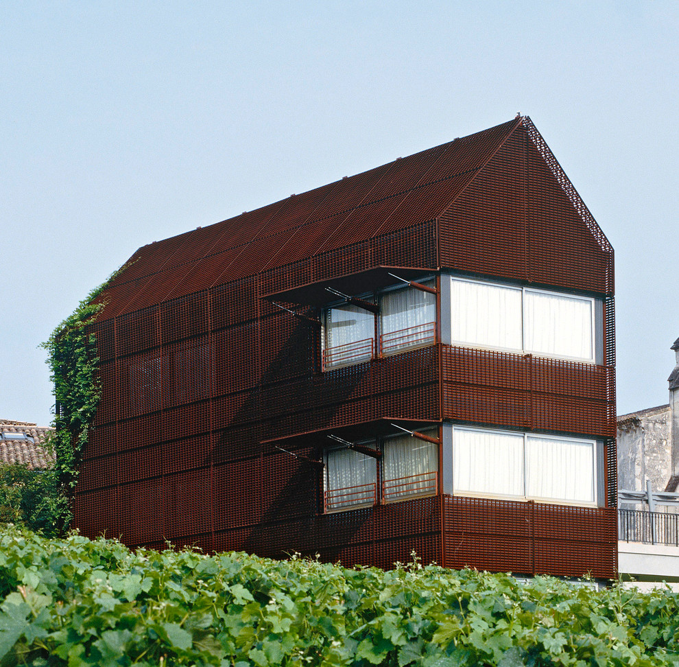 Imagen de fachada marrón urbana grande de dos plantas con revestimiento de metal y tejado a dos aguas