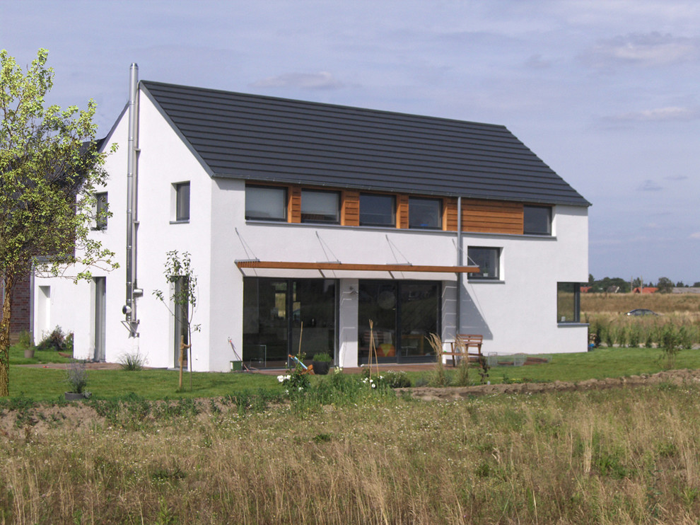Esempio della facciata di una casa bianca contemporanea a due piani con rivestimento in legno