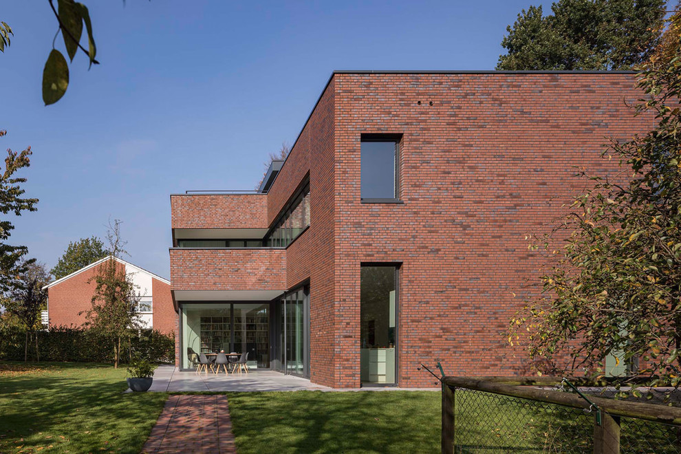Идея дизайна: двухэтажный, кирпичный, красный, большой частный загородный дом в стиле модернизм с плоской крышей