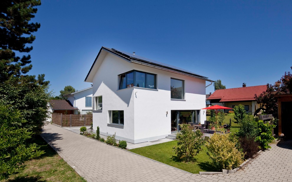 Kleines, Zweistöckiges Modernes Einfamilienhaus mit Putzfassade, weißer Fassadenfarbe, Satteldach, Ziegeldach und grauem Dach in München