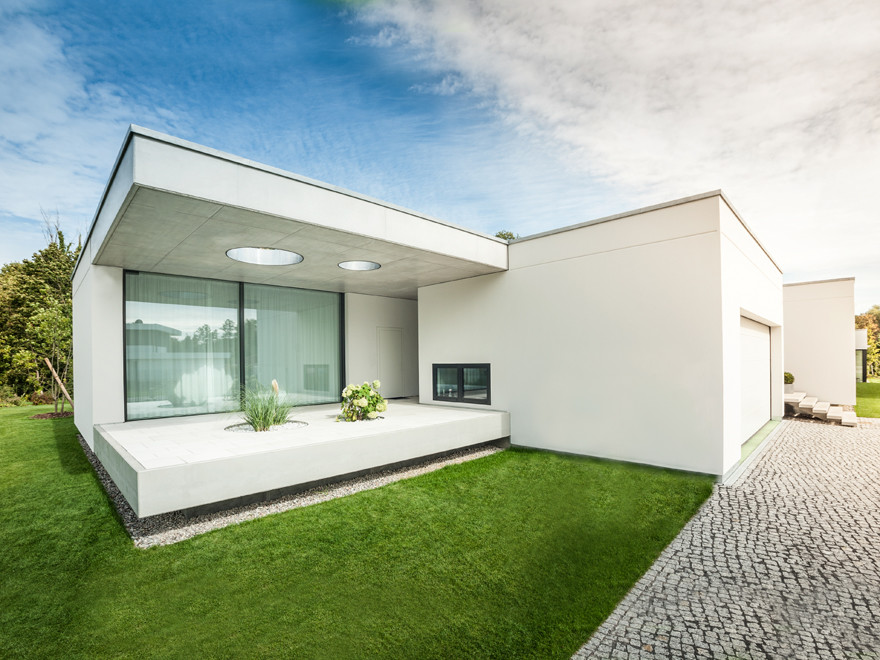 Expansive and white modern bungalow concrete house exterior in Berlin with a flat roof.