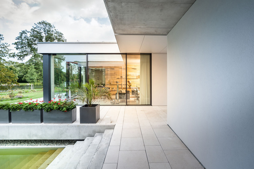 Design ideas for an expansive and white modern bungalow concrete house exterior in Berlin with a flat roof.